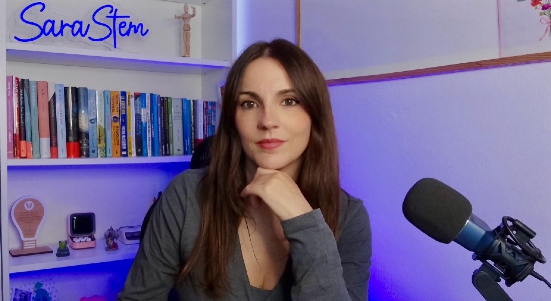 Sara Díaz Martín en su estudio, con el rótulo de neón de SaraStem, una estantería de libros y un micrófono.